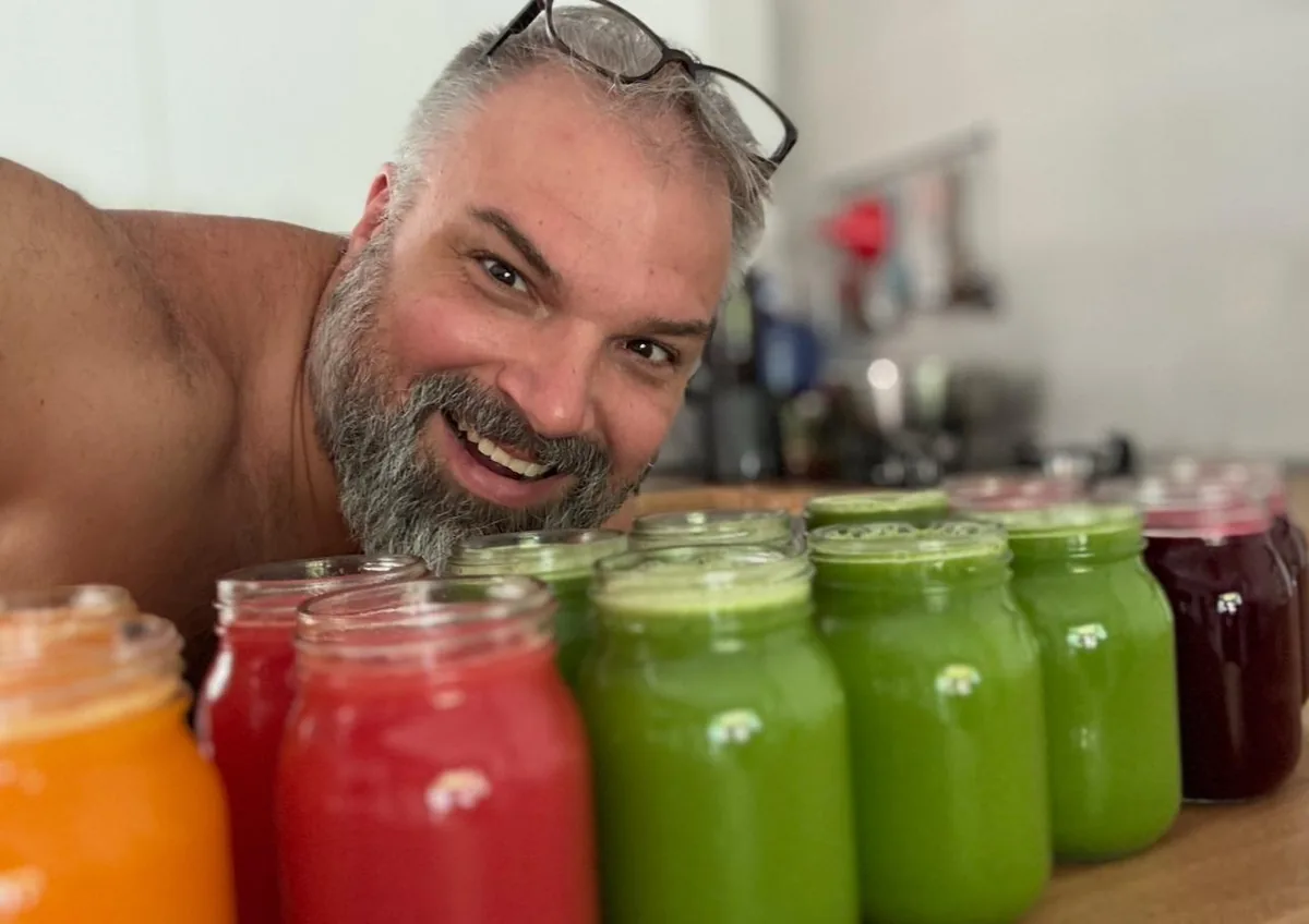 Gunther Stange lächelt hinter einer Reihe frisch gepresster Säfte in Gläsern