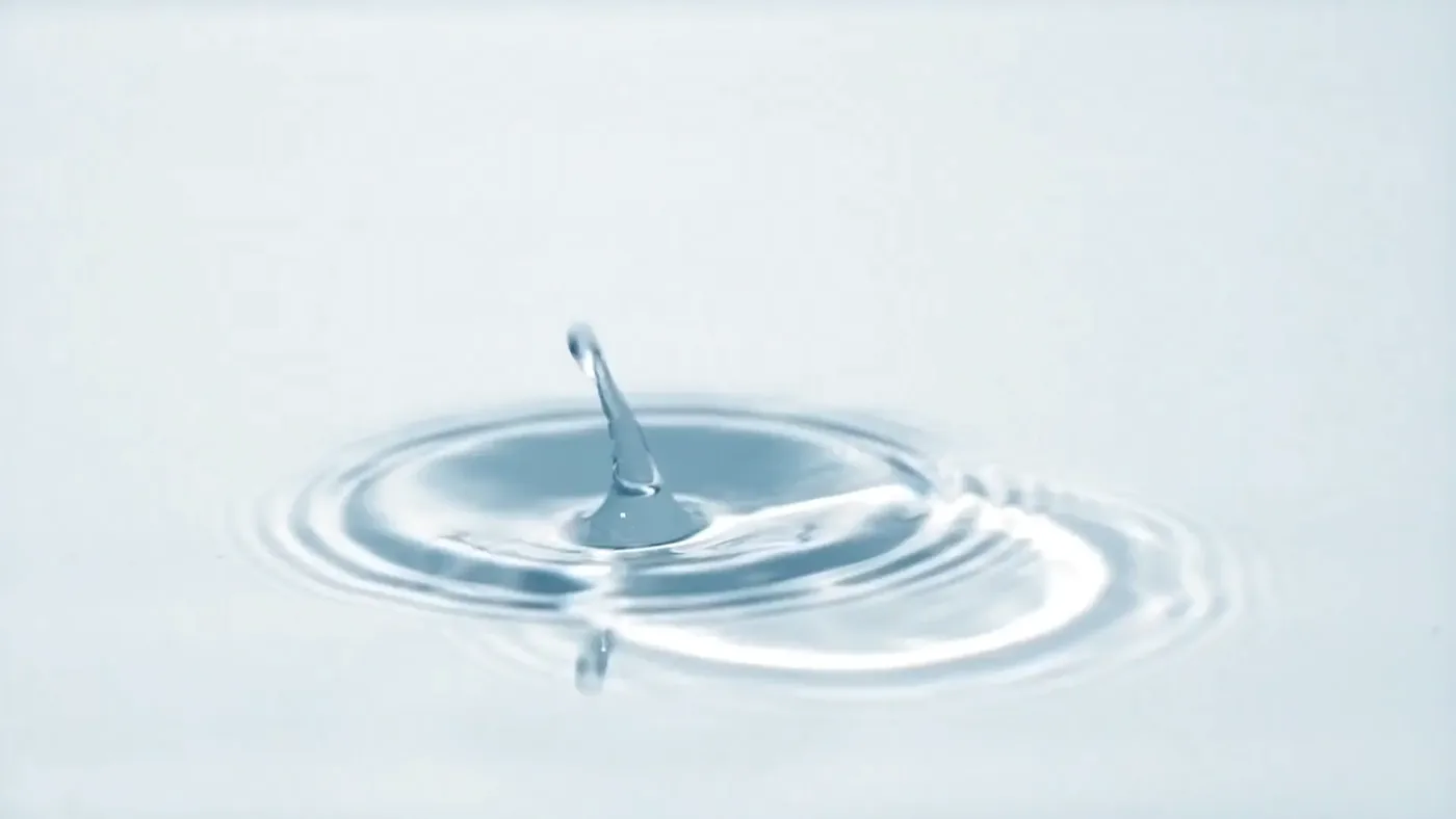 Ein Wassertropfen fällt auf eine ruhige Wasseroberfläche